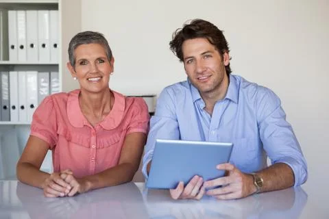 Casual smiling business team working at desk using tablet Stock Photos