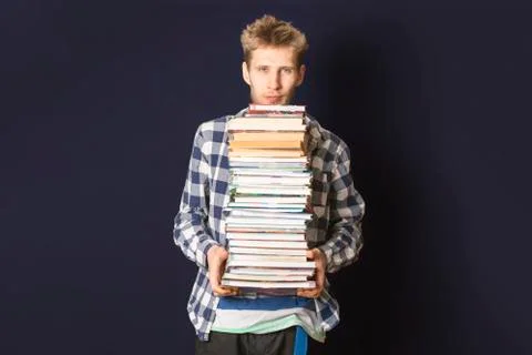 Casual student carry huge stack of books on dark background Stock Photos