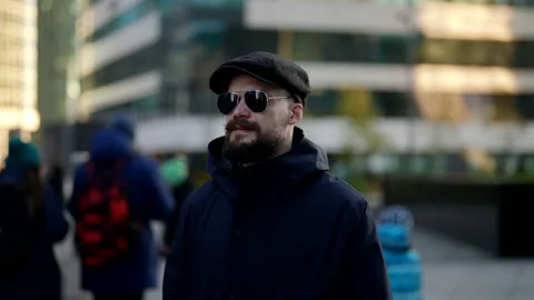 Casual style dressed man with cap and sunglasses is walking in city center in Vídeo Stock 165944472