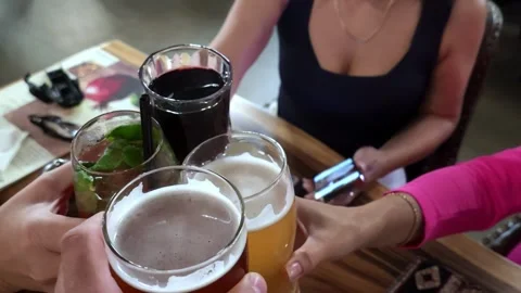 Casual toast with drinks around weathered wooden table among friends under warm Video stock 343628384
