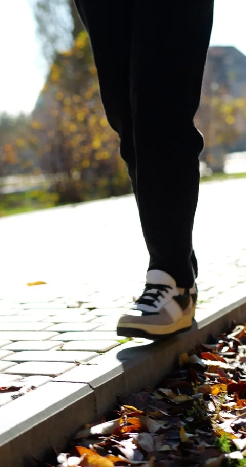 Casual walking on sidewalk during sunny day. Person enjoys autumn scenery with Stock Footage 346472928