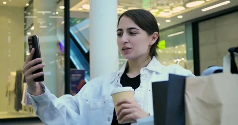 Casual woman sips coffee while shopping. Female customer relaxes with coffee Stock Footage 344742340