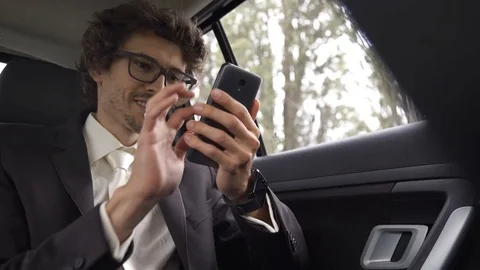 Casual young man using smartphone in a car Stock Footage 82618008