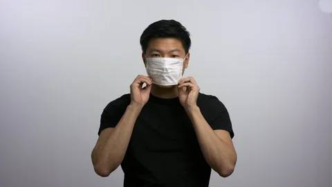 Casually dressed Asian man putting on face mask Stock Footage 129677414