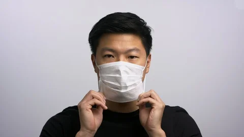 Casually dressed Asian man putting on face mask 動画素材 129678387