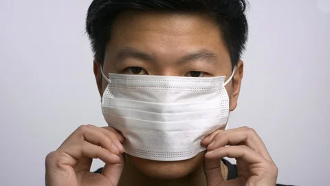 Casually dressed Asian man putting on face mask Stock Footage 129680895