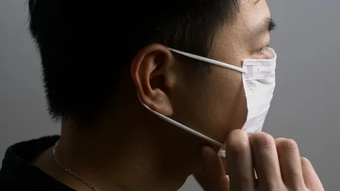 Casually dressed Asian man putting on face mask Stock Footage 129884516