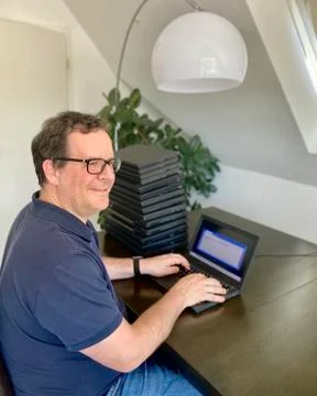 A casually dressed caucasian middle aged man is installing a laptop computer Stock Photos