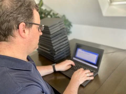 A casually dressed caucasian middle aged man is installing a laptop computer Stock Photos