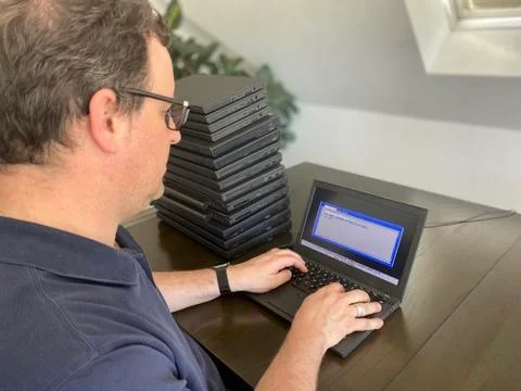 A casually dressed caucasian middle aged man is installing a laptop computer Stock Photos