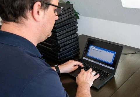 A casually dressed caucasian middle aged man is installing a laptop computer Stock Photos