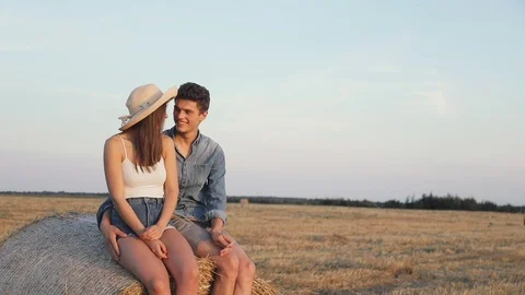 Casually Dressed Couple Sitting on the Bale of Hay on the Farm. Hugging Sincerly Stock Footage 93849668