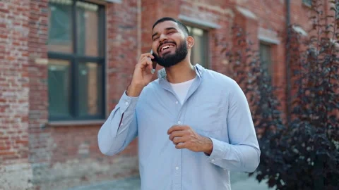 Casually dressed man talking on mobile phone near brick building outdoors Video stock 250387936