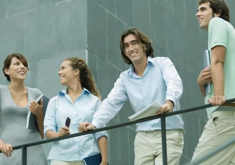 Casually dressed young executives standing next to railing, low angle view Stock Photos