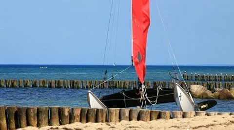 Catamaran on the beach of the Baltic Sea in front of a blue sky Stock Footage 11140092