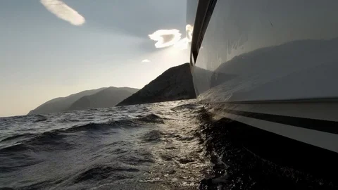Catamaran Sailboat side view the hull  with waves running and sun behind clouds Stock Footage 95835616