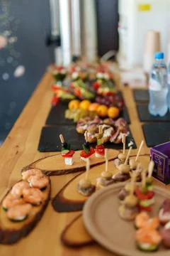 Catering buffet table with various gourmet appetizers on wooden boards. Stock Photos