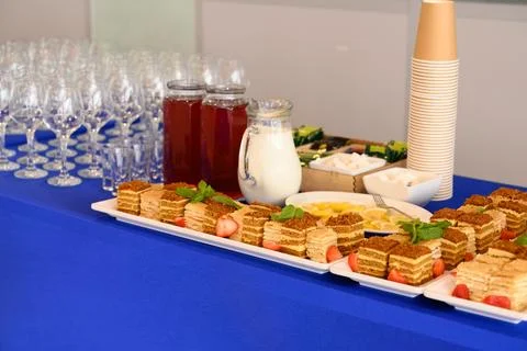 Catering coffee break buffet table with slices of honey cake, milk glass ju.. Stock Photos