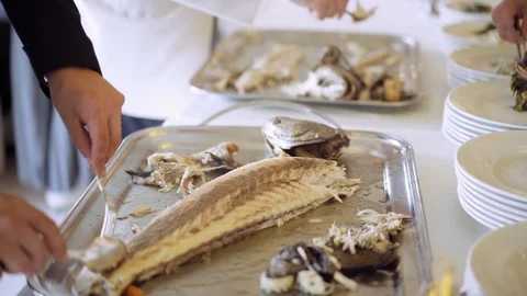 Catering event. The chef shares the freshly-packed fish lying on the metal tray Stock-Footage 94724341