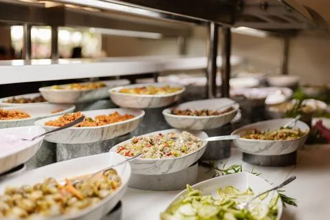 A catering setup shows multiple dishes arranged in bowls at a buffet statio.. Stockfoto's