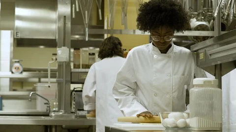 Catering student learning how to roll pastry, teacher reassuring her. Stock-Footage 88016120