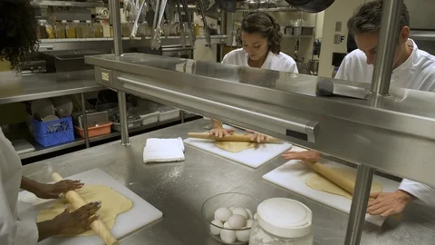 Catering students learning how to roll pastry in commercial kitchen. 動画素材 88016172