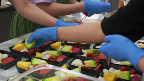 Catering workers in blue gloves preparing fresh fruit dessert boxes Stock Footage 343018126