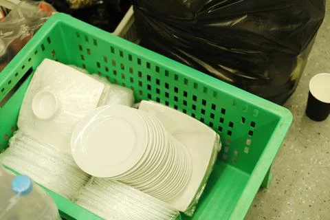 Catering workers prepare for an event with clean white plates stacked in a green Stock Photos