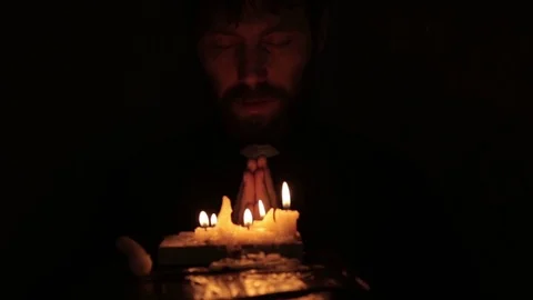 Catholic vicar lights candles and reading from the holy bible in a dark Stock Footage