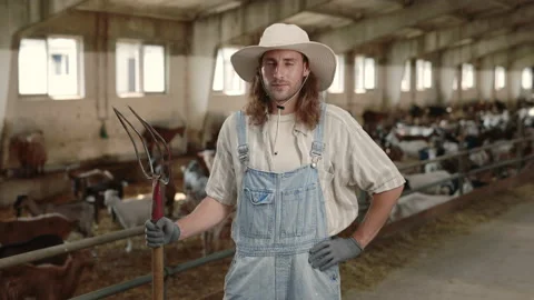 Cattleman in uniform using pitchfork for cleaning goat farm 動画素材 157562089
