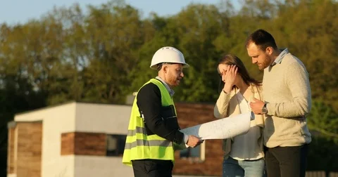 Caucasian architect in white helmet showing the drawing of house to young man Stock Footage