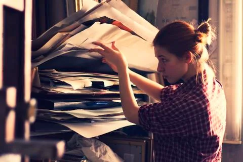 Caucasian artist sorting through papers in studio Stock Photos