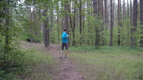 Caucasian athlete warming up before jogging in the forest Vídeos de archivo 117066400