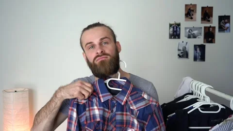Caucasian attractive Man is looking into the mirror choosing a shirt Video stock 147900367