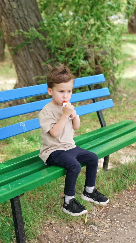 Caucasian baby boy sitting on the bench outdoors on a windy day.  Stock Footage 293772699