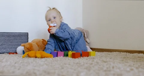 Caucasian baby looking at camera while playing with toys and crawling on the rog Video stock 128504494