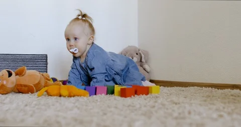 Caucasian baby looking at camera while playing with toys and crawling on the rog Video stock 128505855