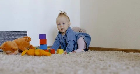 Caucasian baby looking at camera while playing with toys and crawling on the rog Video stock 128507070