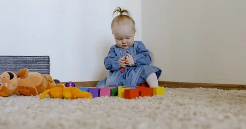 Caucasian baby looking at camera while playing with toys and crawling on the rog Video stock 128507357