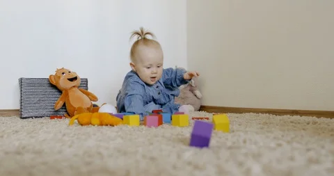 Caucasian baby looking at camera while playing with toys and crawling on the rog Video stock 128508815