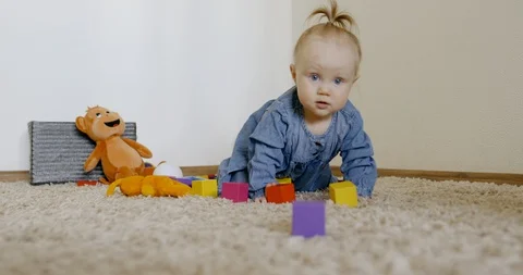 Caucasian baby looking at camera while playing with toys and crawling on the rog Video stock 128508963