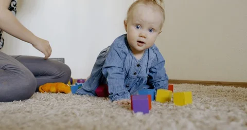 Caucasian baby looking at camera while playing with toys and crawling on the rog Video stock 128508998