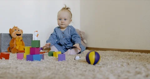 Caucasian baby looking at camera while playing with toys and crawling on the rog Video stock 128513489