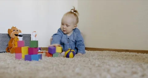 Caucasian baby looking at camera while playing with toys and crawling on the rog Video stock 128515327
