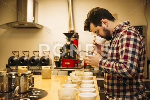 Caucasian Barista Tasting Coffee In Coffee Shop