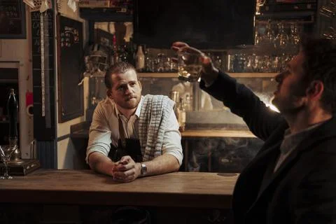 Caucasian bartender serving drunk customer drinking alone Stock Photos