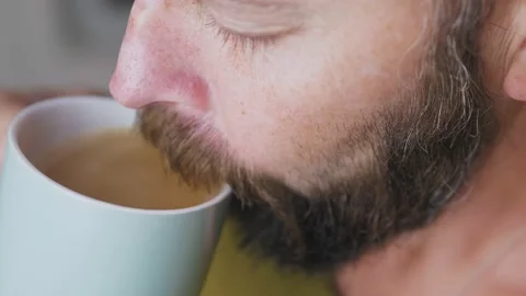 Caucasian bearded man drinking coffee in the kitchen. Close-up of a man with a Stock Footage 226689692
