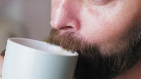 Caucasian bearded man drinking coffee in the kitchen. Close-up of a man with a Stock Footage 226913102