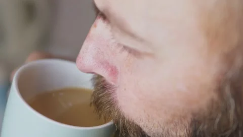 Caucasian bearded man drinking coffee in the kitchen. Close-up of a man with a Stock Footage 227132095