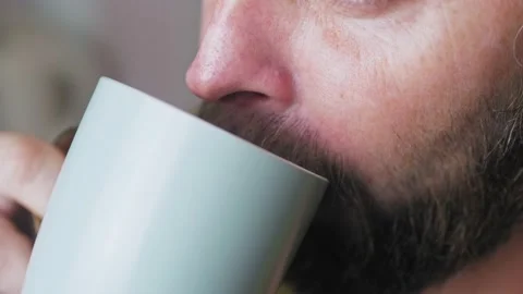 Caucasian bearded man drinking coffee in the kitchen. Close-up of a man with a Stock Footage 227718223